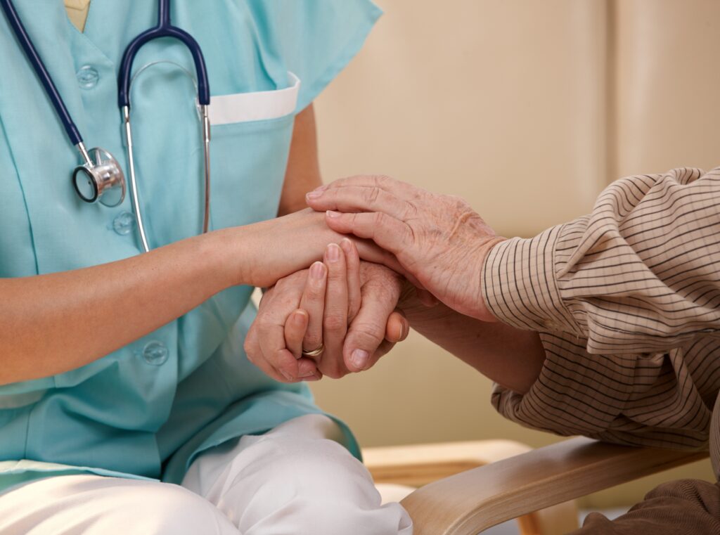 Closeup of joined hands of nurse and elderly patient.
